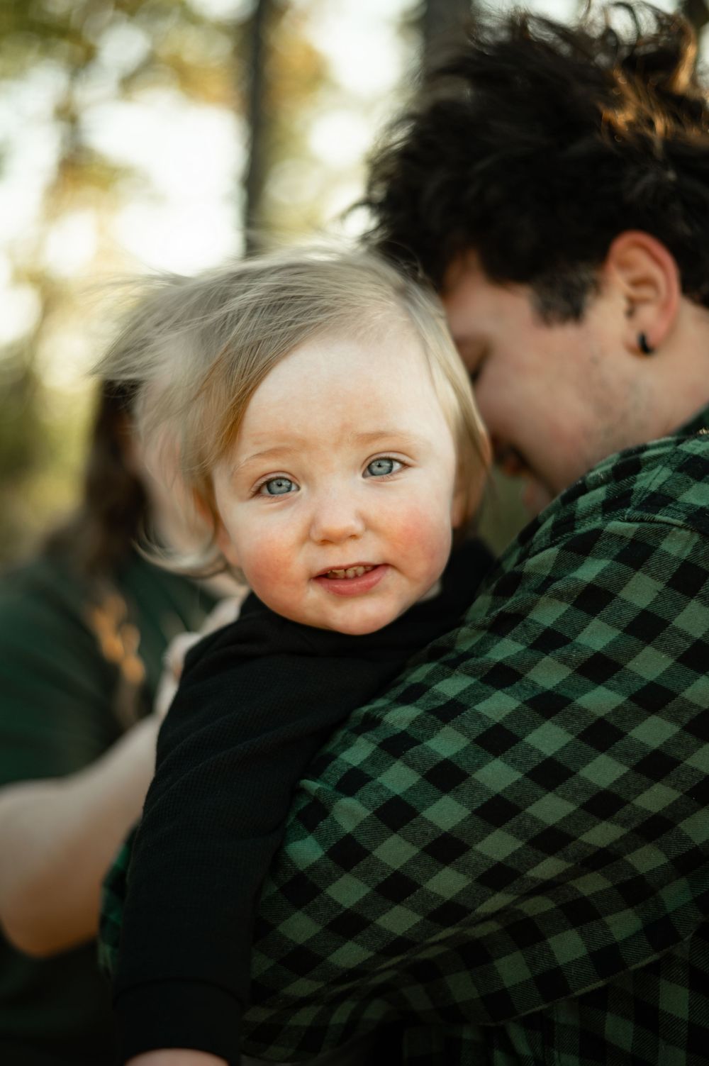 Close-up shots of a young child being held while wearing dark clothing against a sunlit outdoor background.