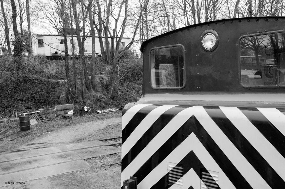 A series of black and white striped railroad crossing barriers line up along a rural road in winter.