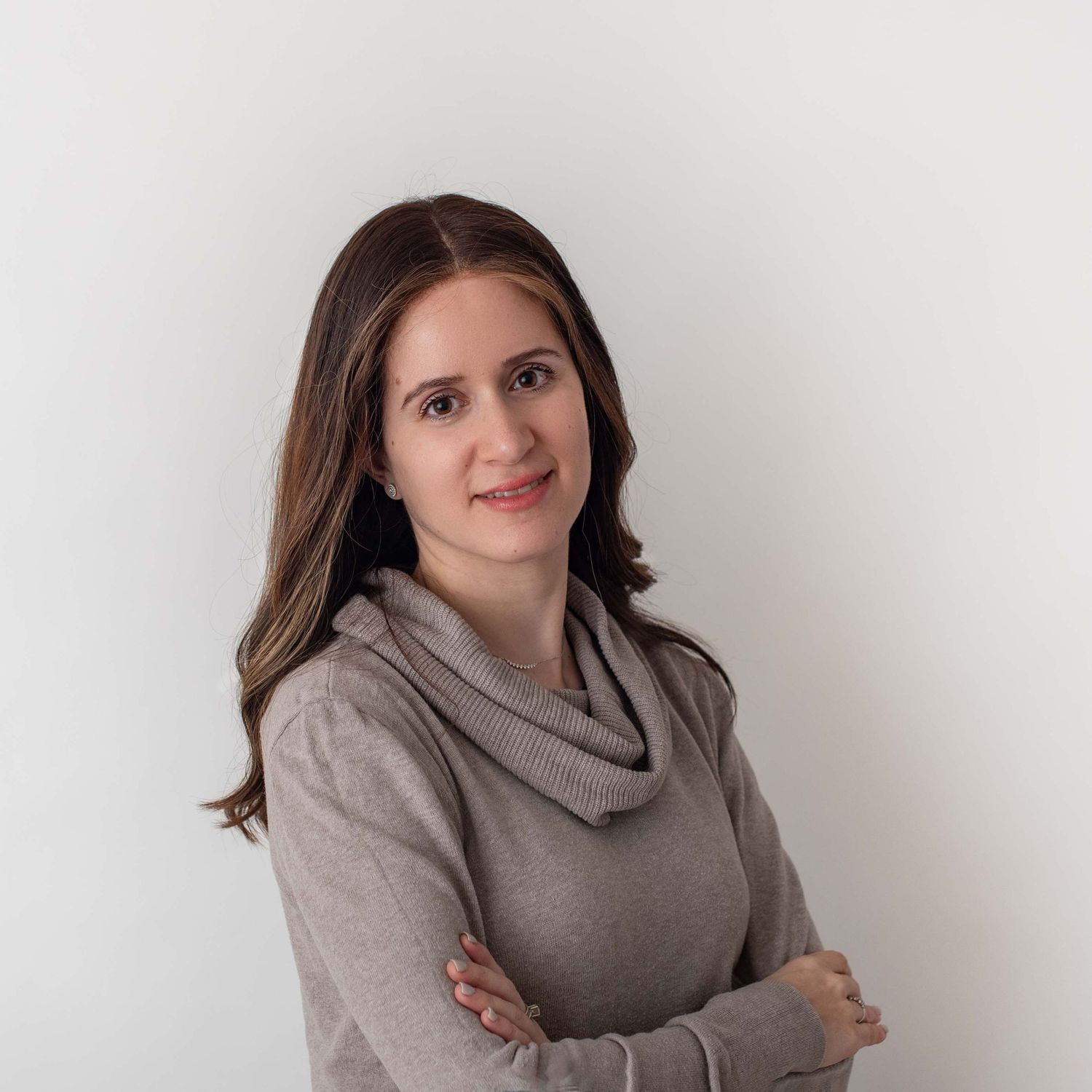 Professional portrait of woman in gray sweater against white background.