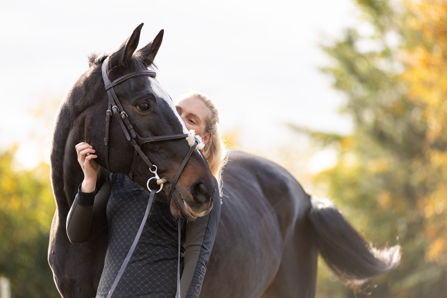 A horse and its rider enjoy an outdoor photoshoot session near rustic wooden fencing on a sunny day.