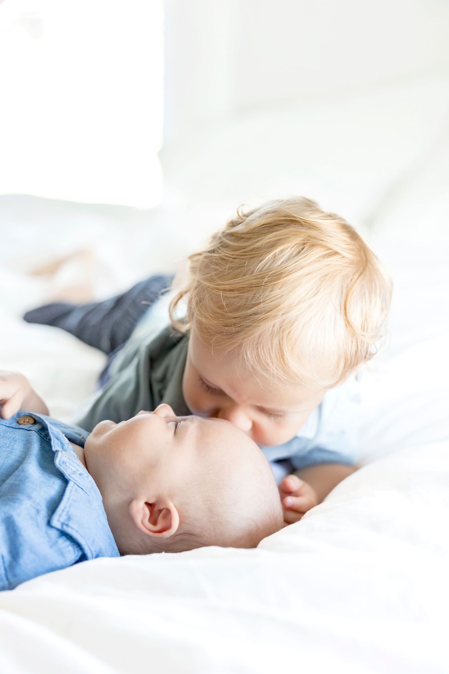 Big brother giving his new baby brother a kiss on the forehead.