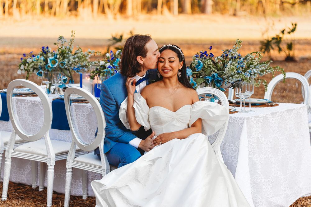 Wedding guests sit at elegantly decorated outdoor tables during golden hour at a garden reception.
