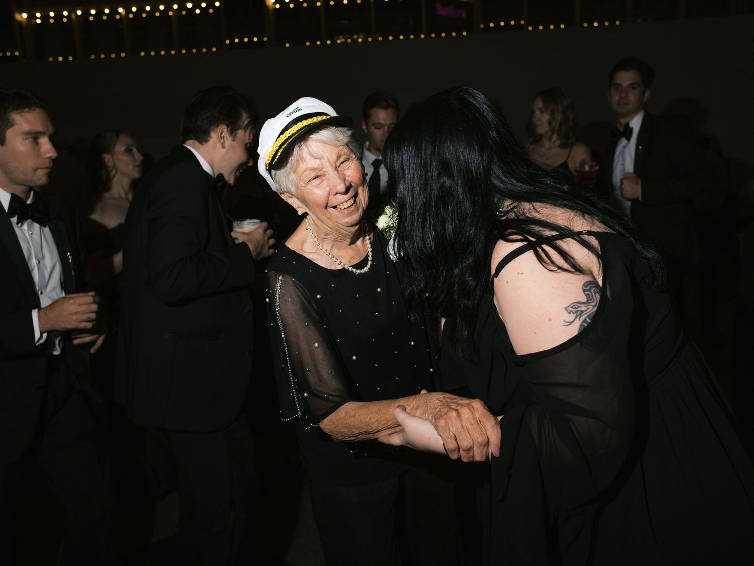 Wedding guests dance and celebrate on a dimly lit dance floor during an evening reception.