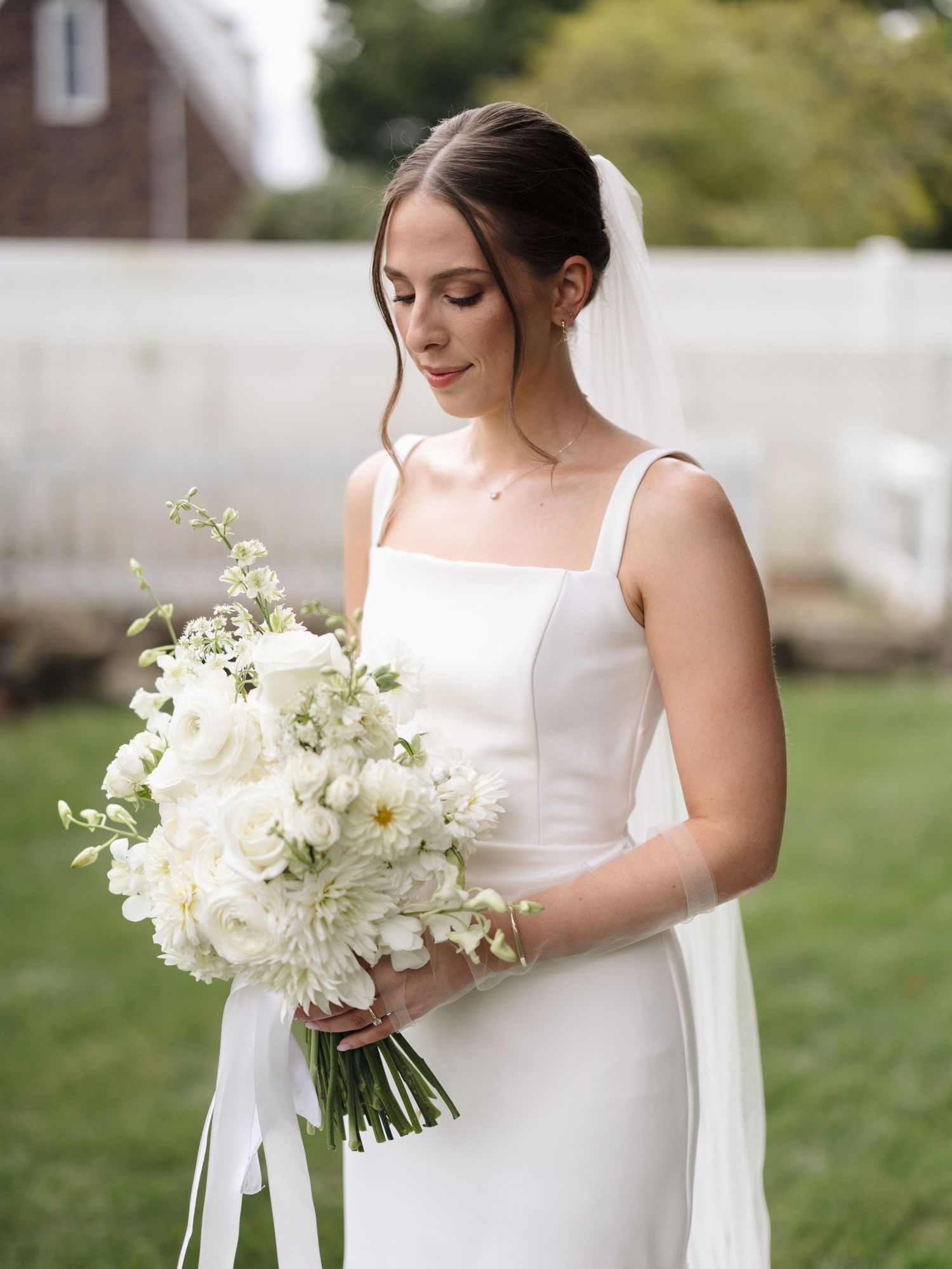 Bridal portrait details showing white floral bouquet and classic wedding dress in outdoor garden setting.