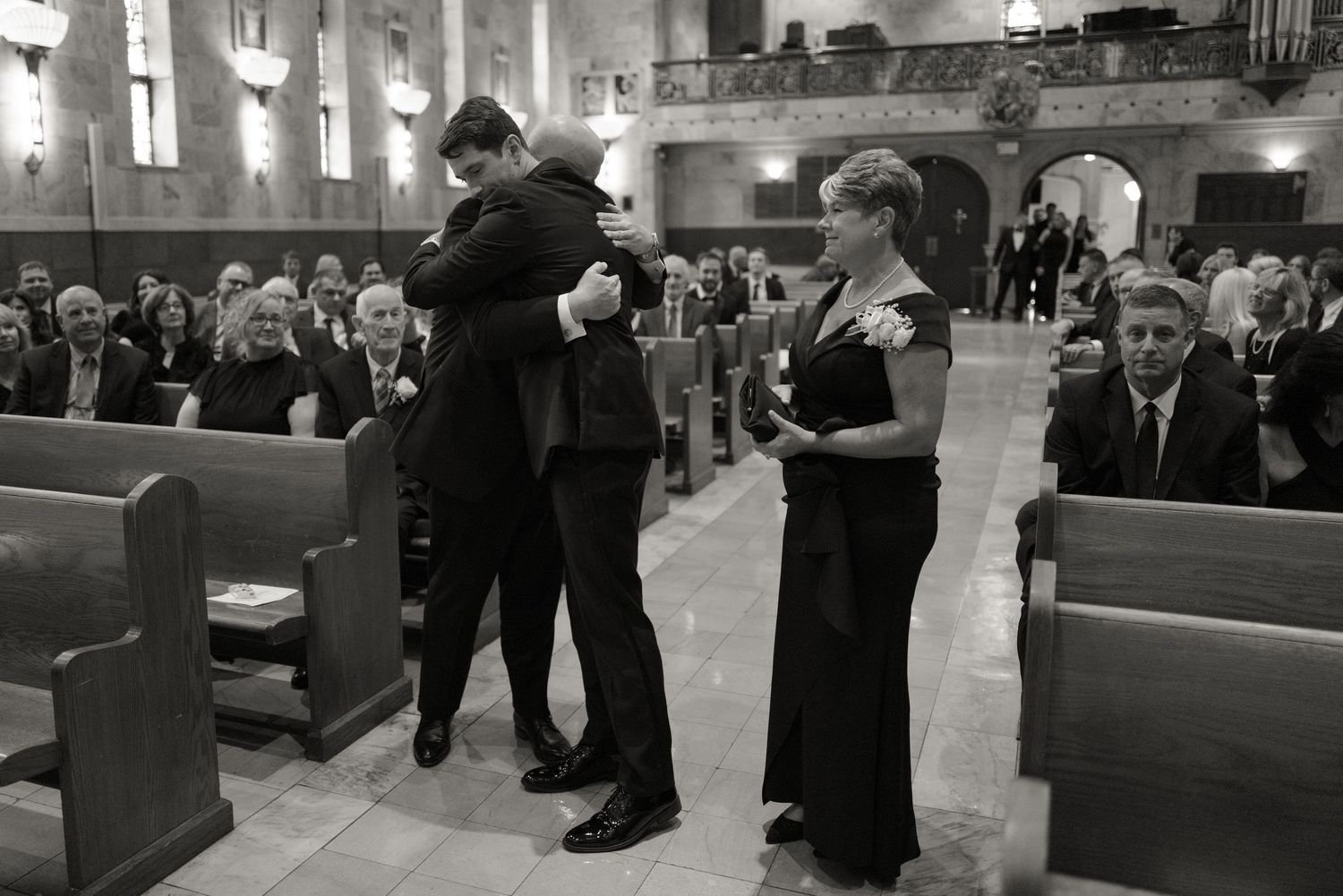 Wedding guests gather inside a traditional church sanctuary with wooden pews and stained glass windows.