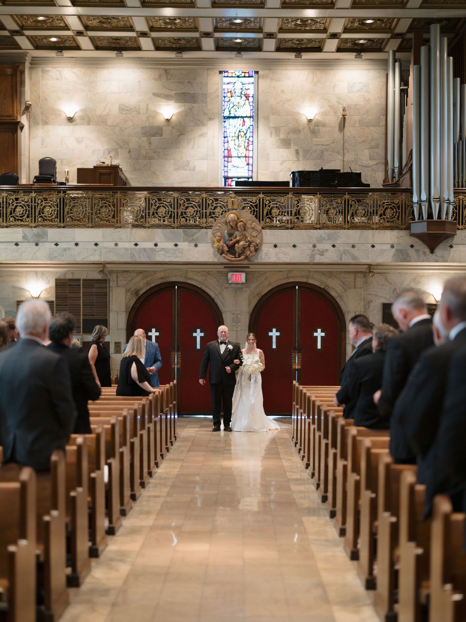 A church interior with rows of wooden pews and decorative crosses on display during a wedding ceremony.