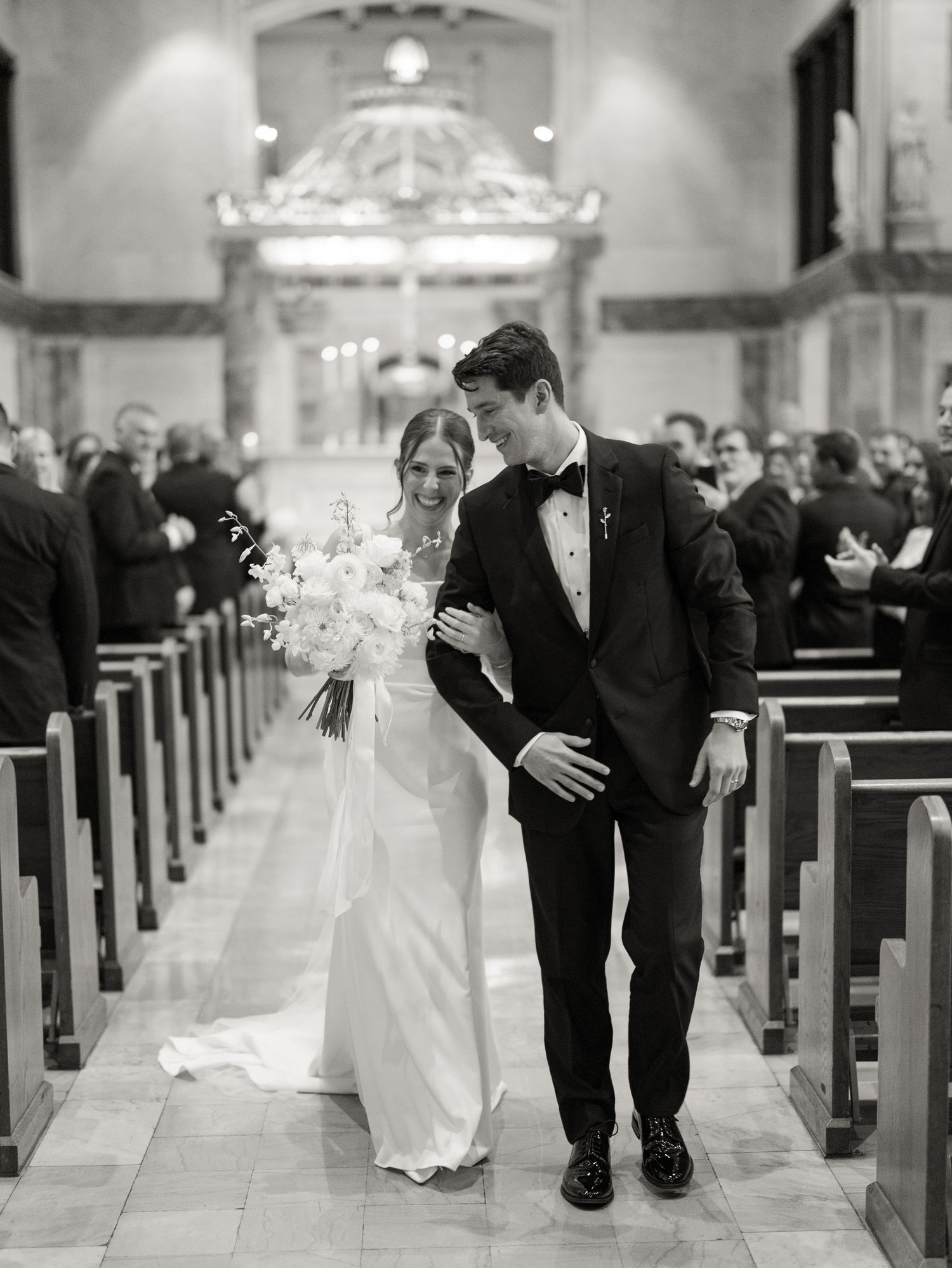 Black and white photo series capturing newlyweds walking through church after wedding ceremony.
