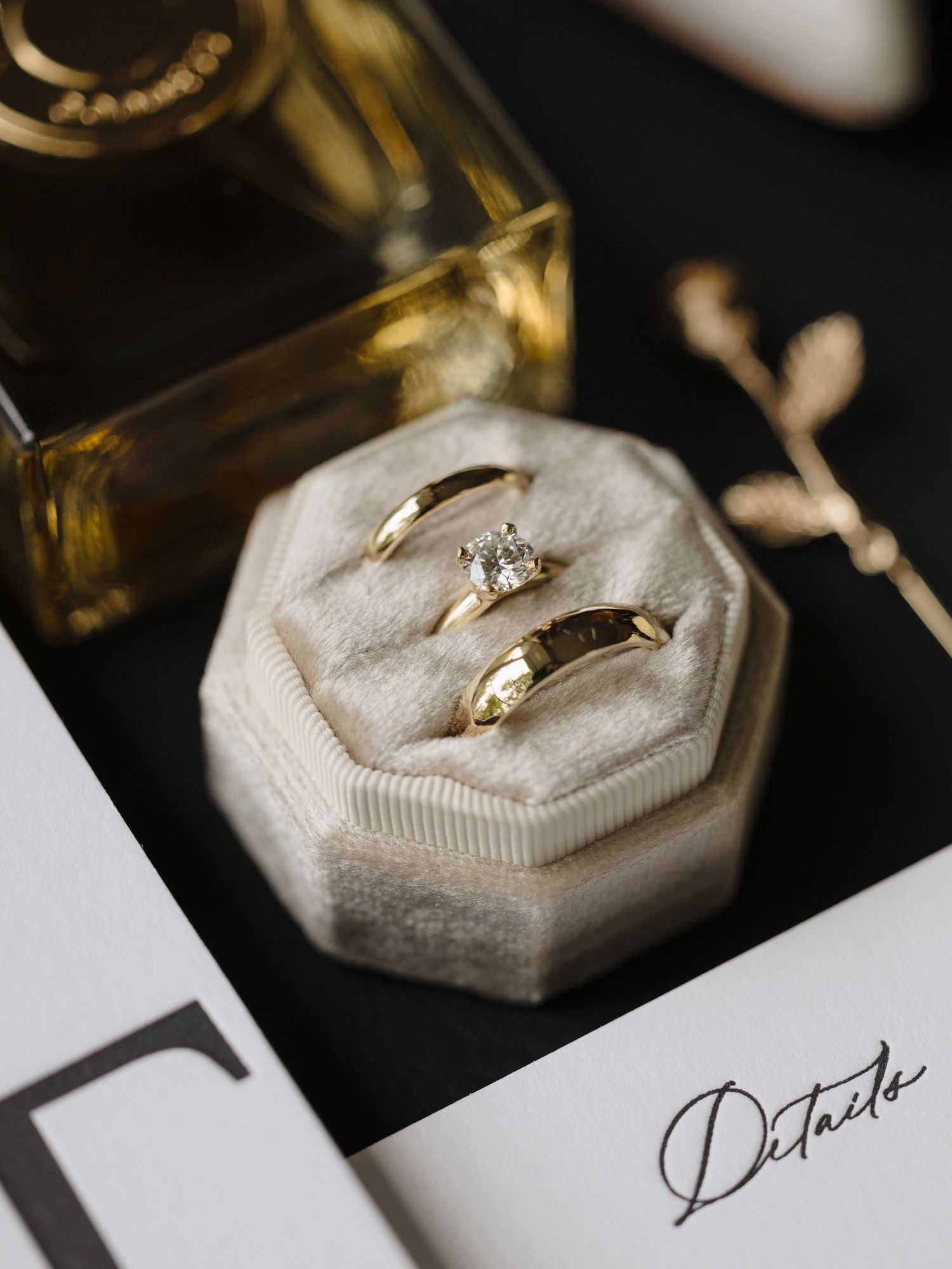 Elegant wedding rings displayed on white octagonal ring boxes in a dark moody setting.