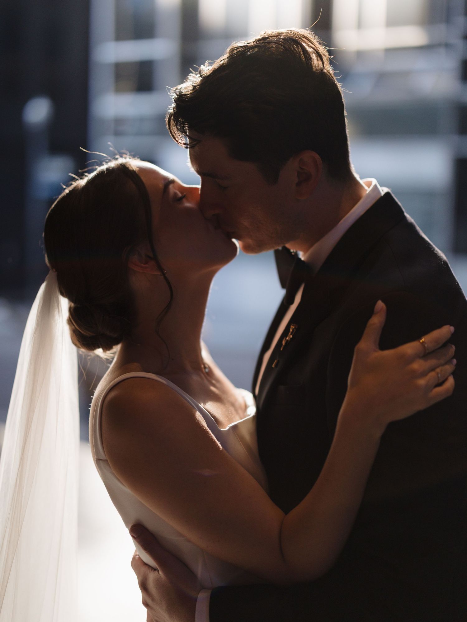 Silhouetted wedding couple embraces during romantic portrait session.