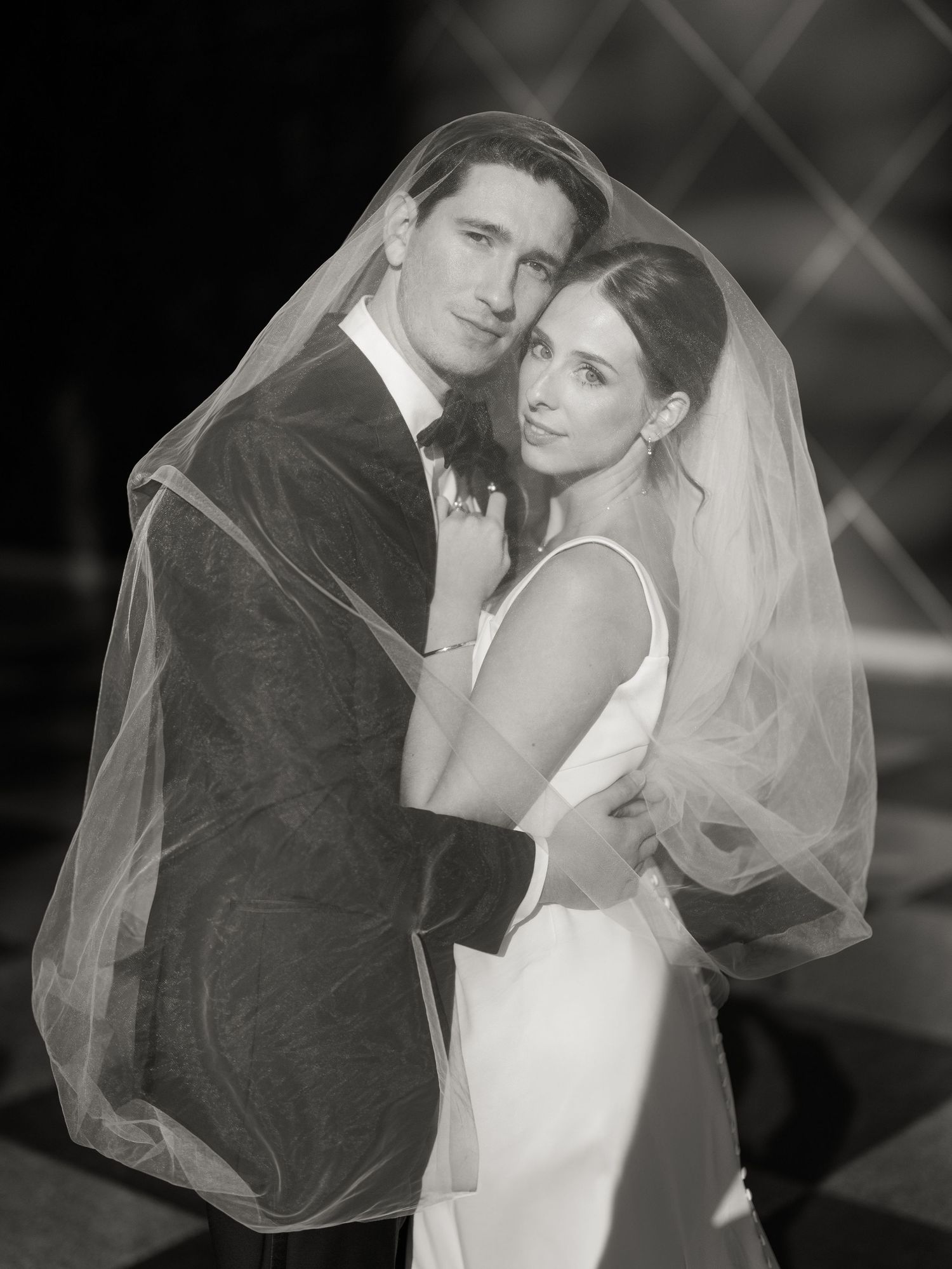 Romantic black and white portraits of newlyweds embracing with bride's veil flowing.