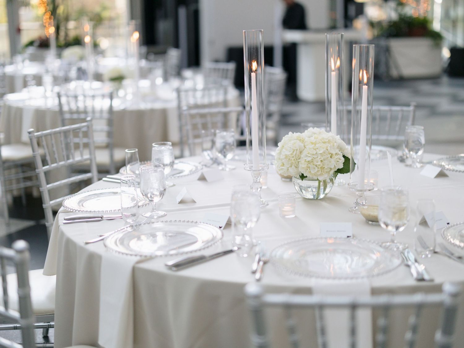 White and silver table settings with crystal glassware at an elegant wedding reception.