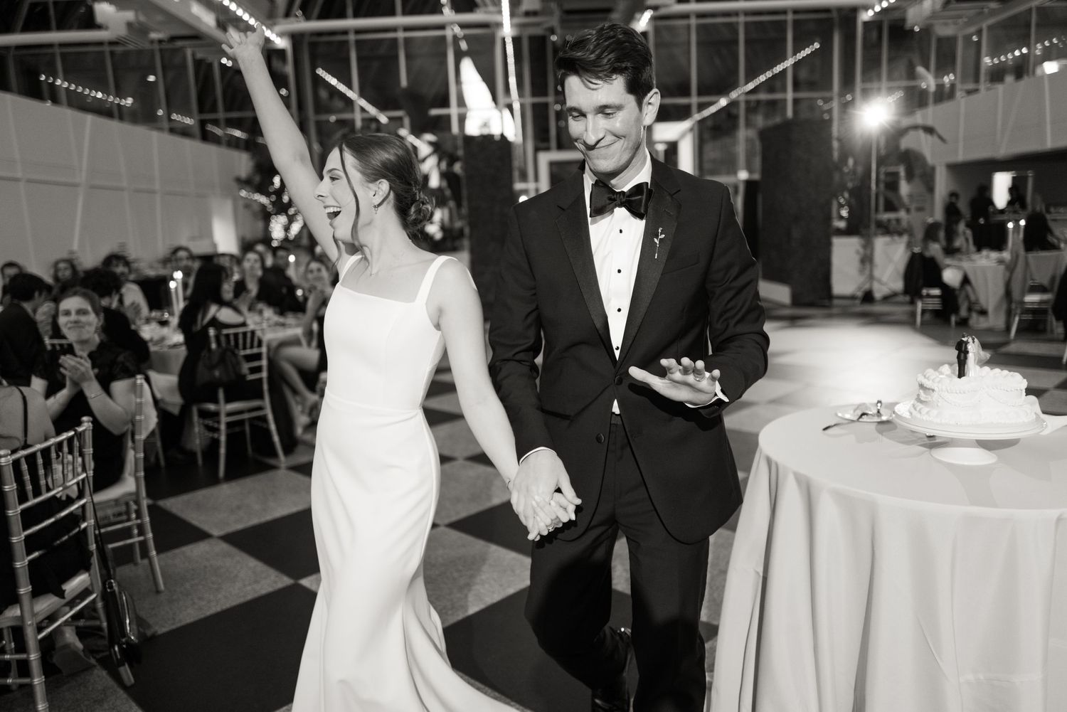 Wedding reception venue with elegant table settings and dance floor under crystal chandeliers.