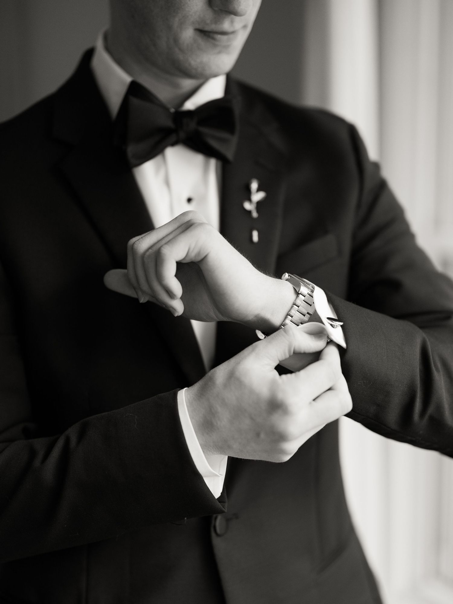 Close-up shots of hands adjusting cufflinks and bow tie details on a formal black tuxedo.