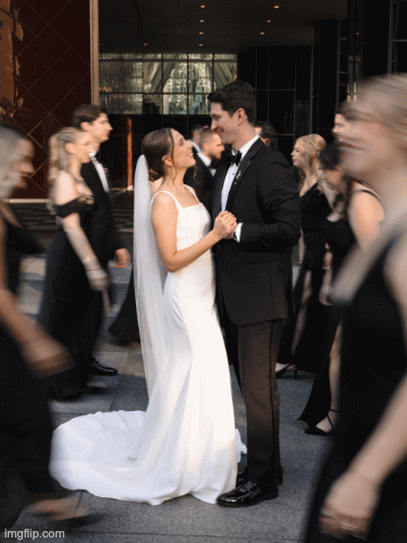 A couple dances surrounded by motion-blurred guests at their wedding reception.