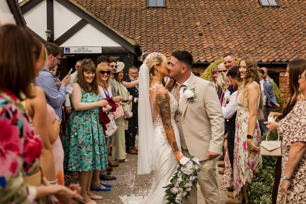 Wedding celebration outside a rustic venue with guests in summer attire.