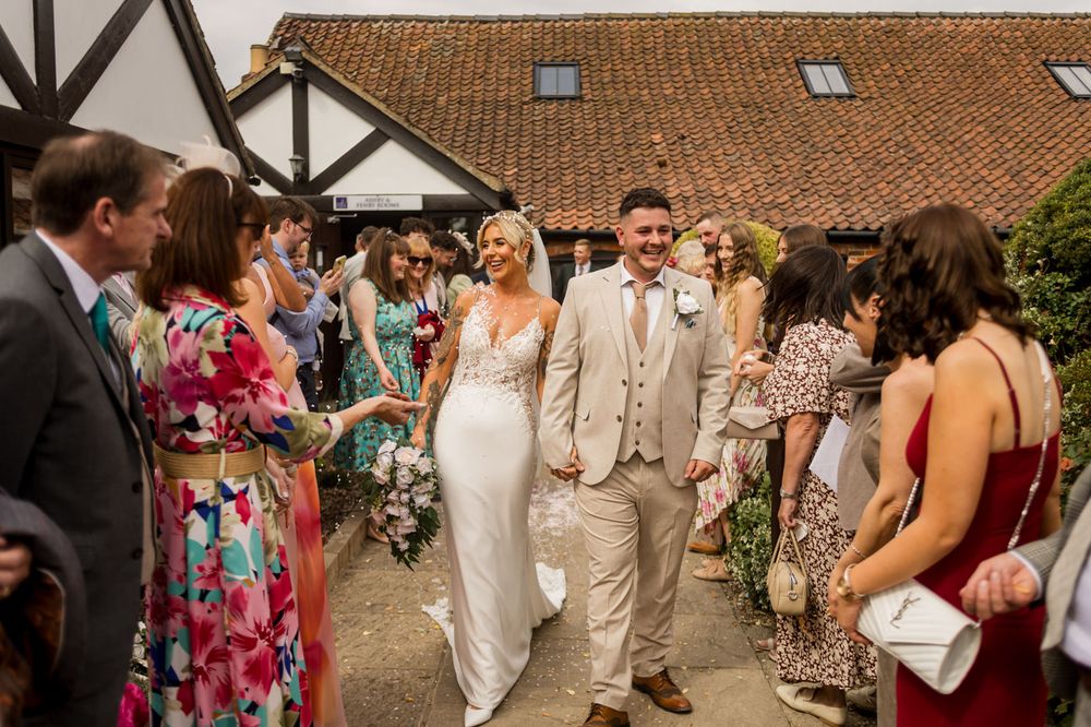 Guests in colorful attire line up along a walkway at an outdoor wedding venue.