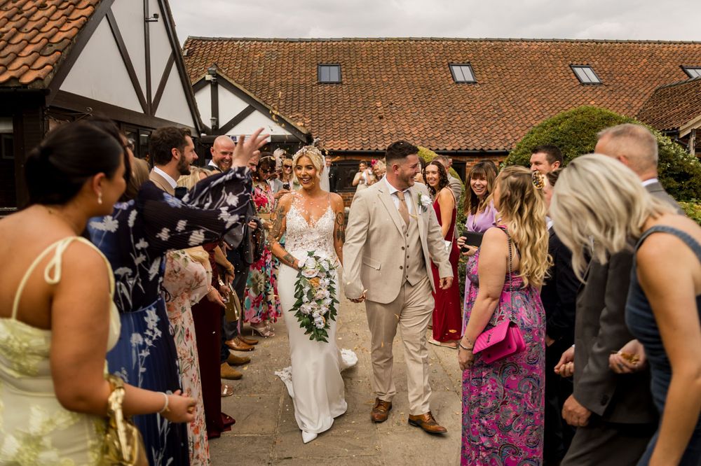Wedding guests line the walkway outside a traditional venue during a celebration.