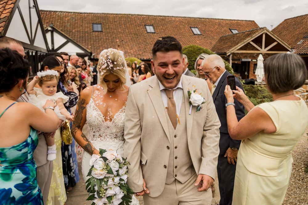 Wedding party exits venue while guests capture the moment on their phones.