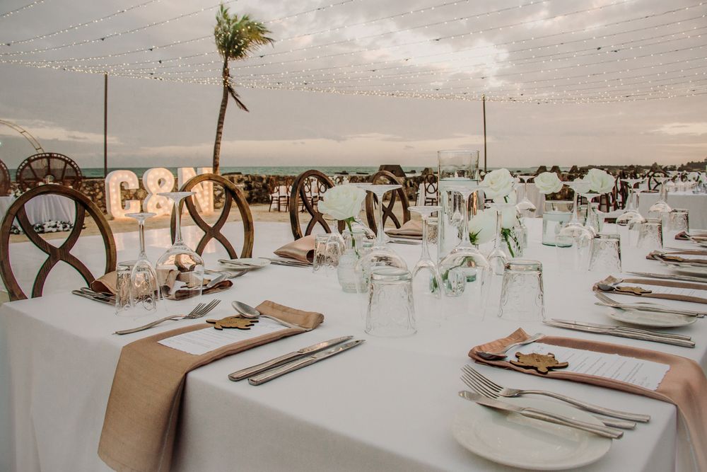 Elegant white wedding reception tables with rustic decor and place settings arranged in a spacious venue. El Dorado Royale Wedding Photograp