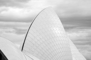 Abstract architectural detail of white curved surfaces against cloudy sky.