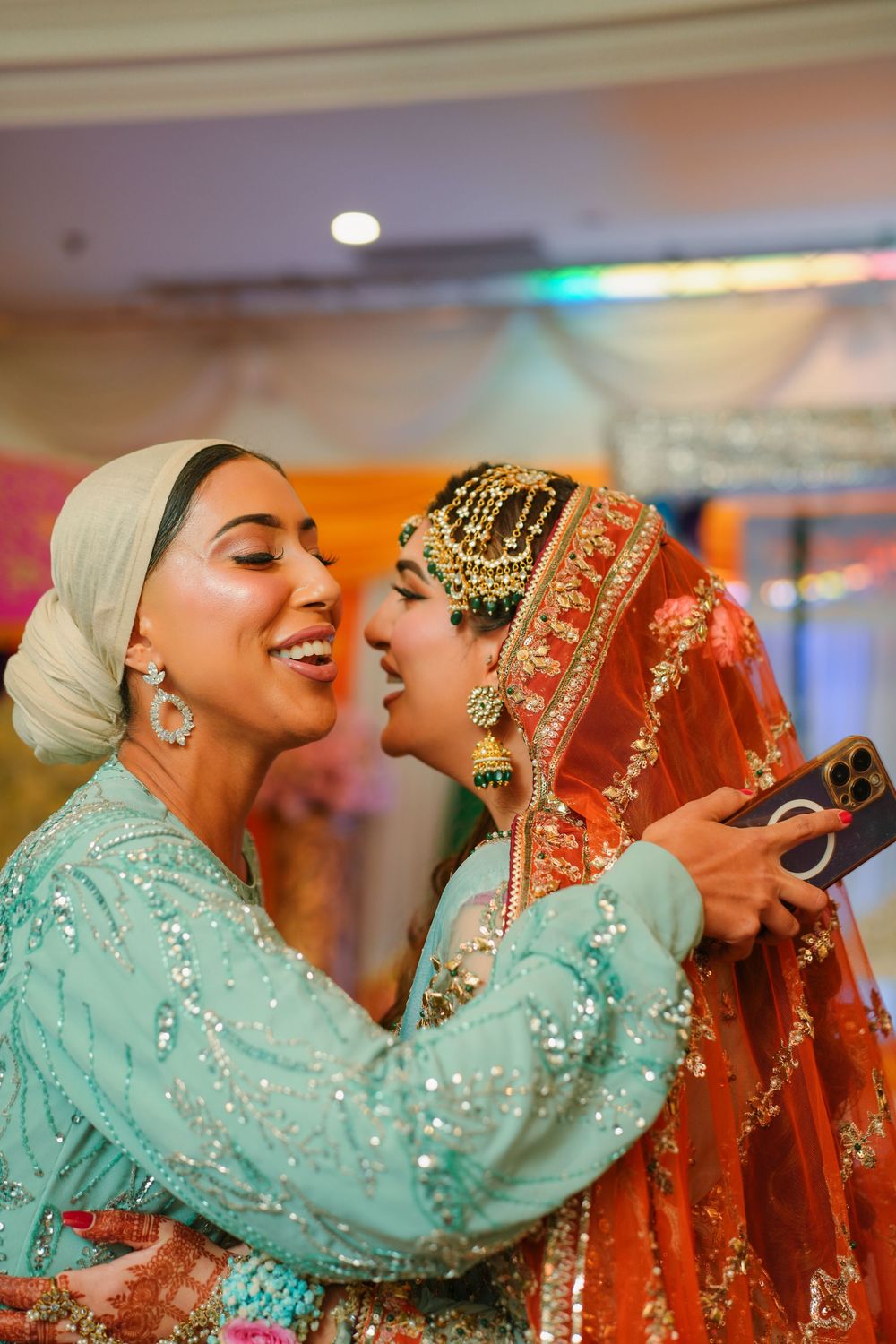 Two people in traditional South Asian wedding attire share an intimate moment at a celebratory reception.