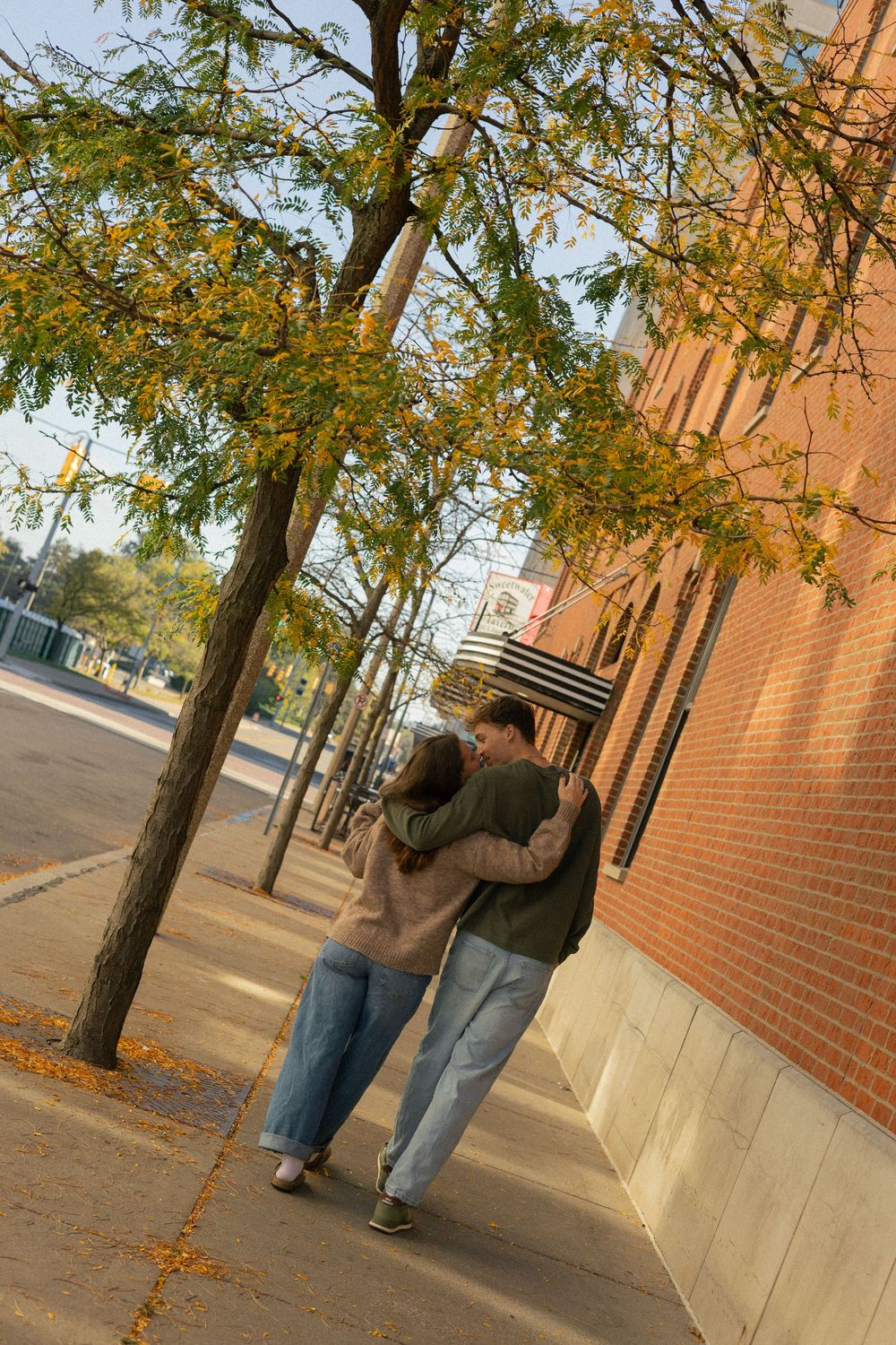 A couple walks the streets of Downtown Flint, loving and hugging while a photographer shoots cinematically behind them.