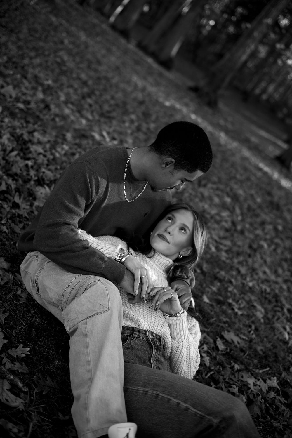 A couple lying together on autumn leaves in black and white photography creates a romantic outdoor scene.