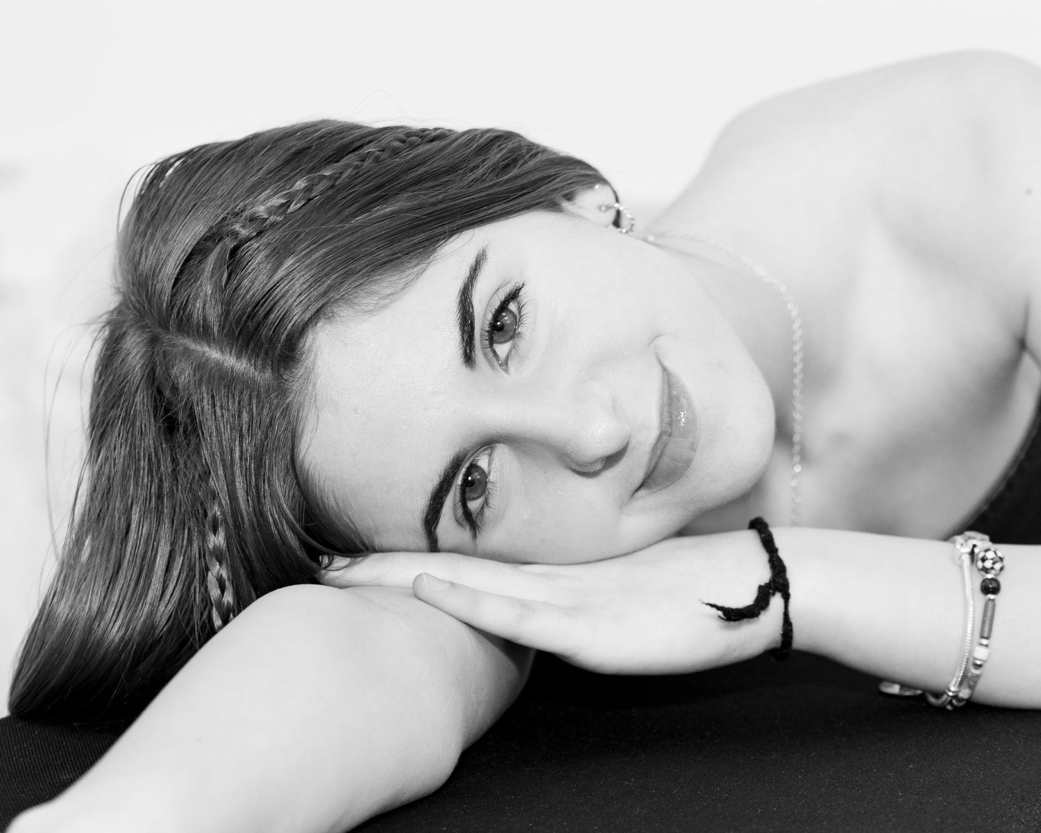 A black and white artistic portrait showing someone laying down in an elegant pose.
