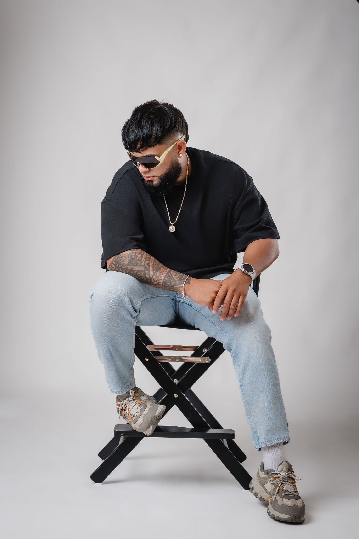 Urban style portrait on director's chair wearing sunglasses and casual streetwear.