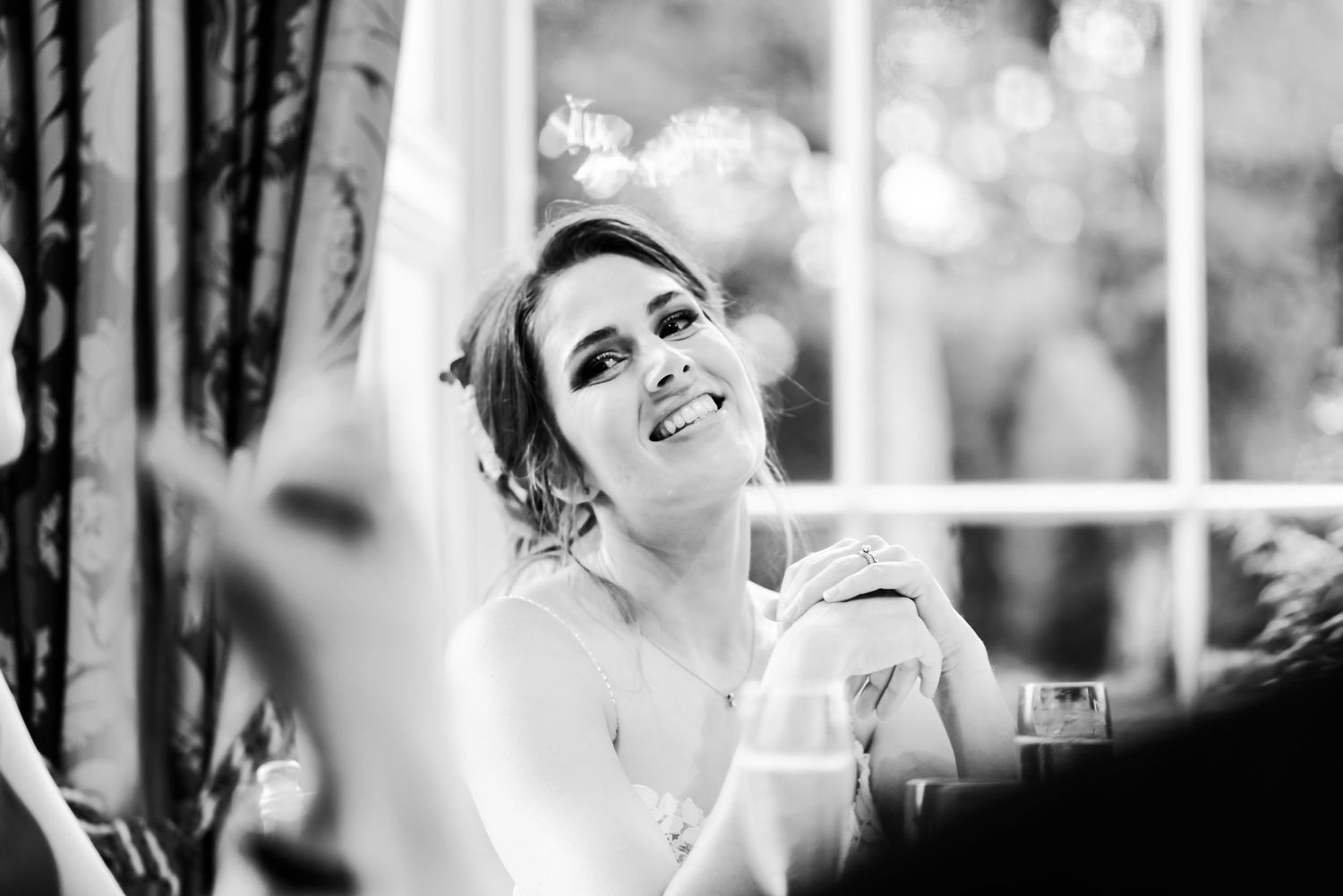 Black and white candid portrait of a bride during an emotional wedding reception moment.