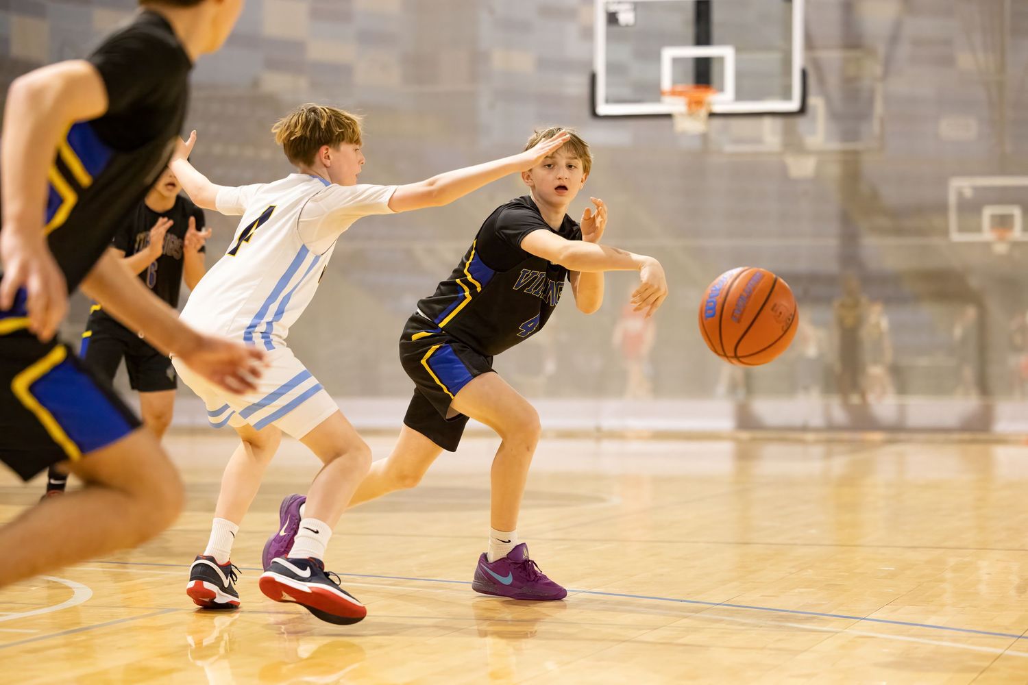 Two basketball players competing for possession of the ball during an intense indoor game.
