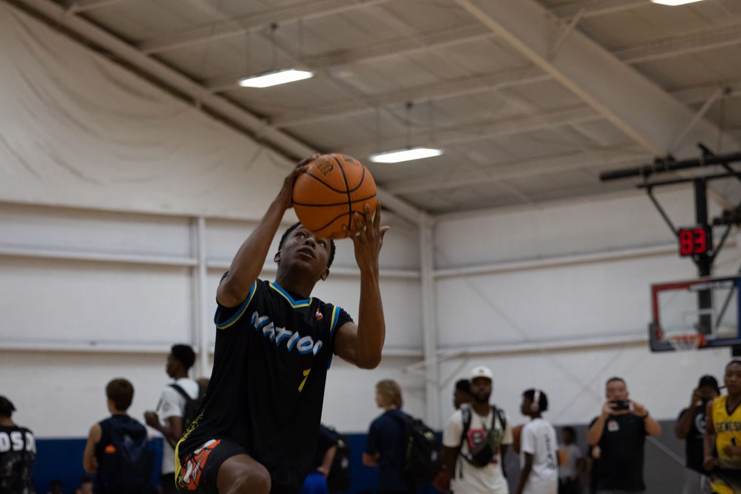 Basketball player in black jersey catches the ball during an indoor game at a gymnasium.