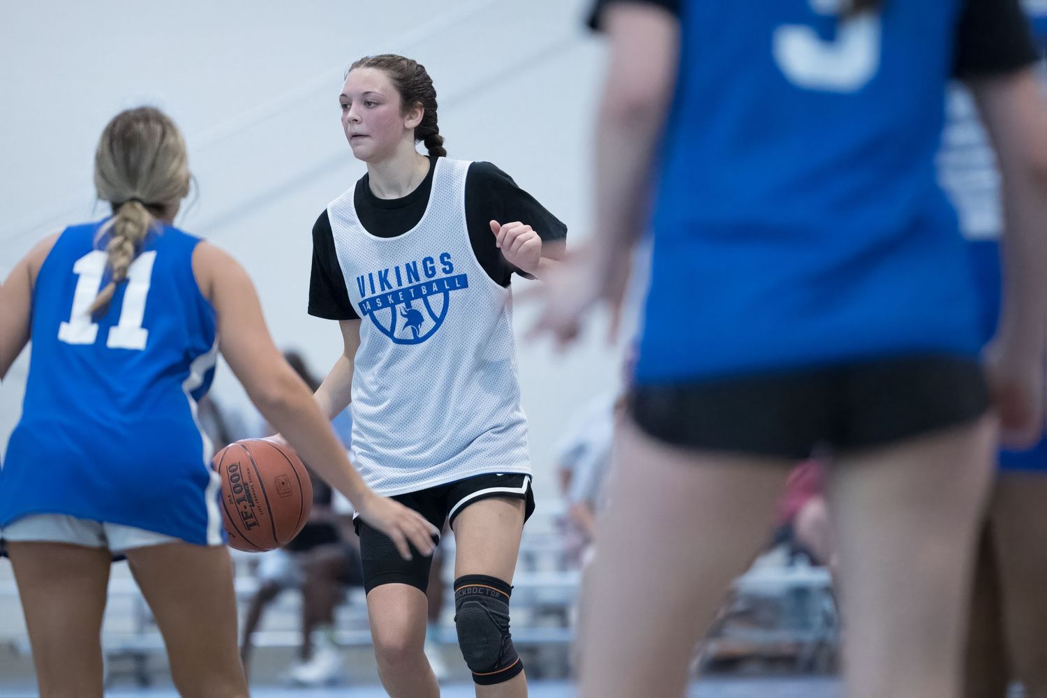 Female basketball players in practice jerseys participating in a scrimmage game on an indoor court.