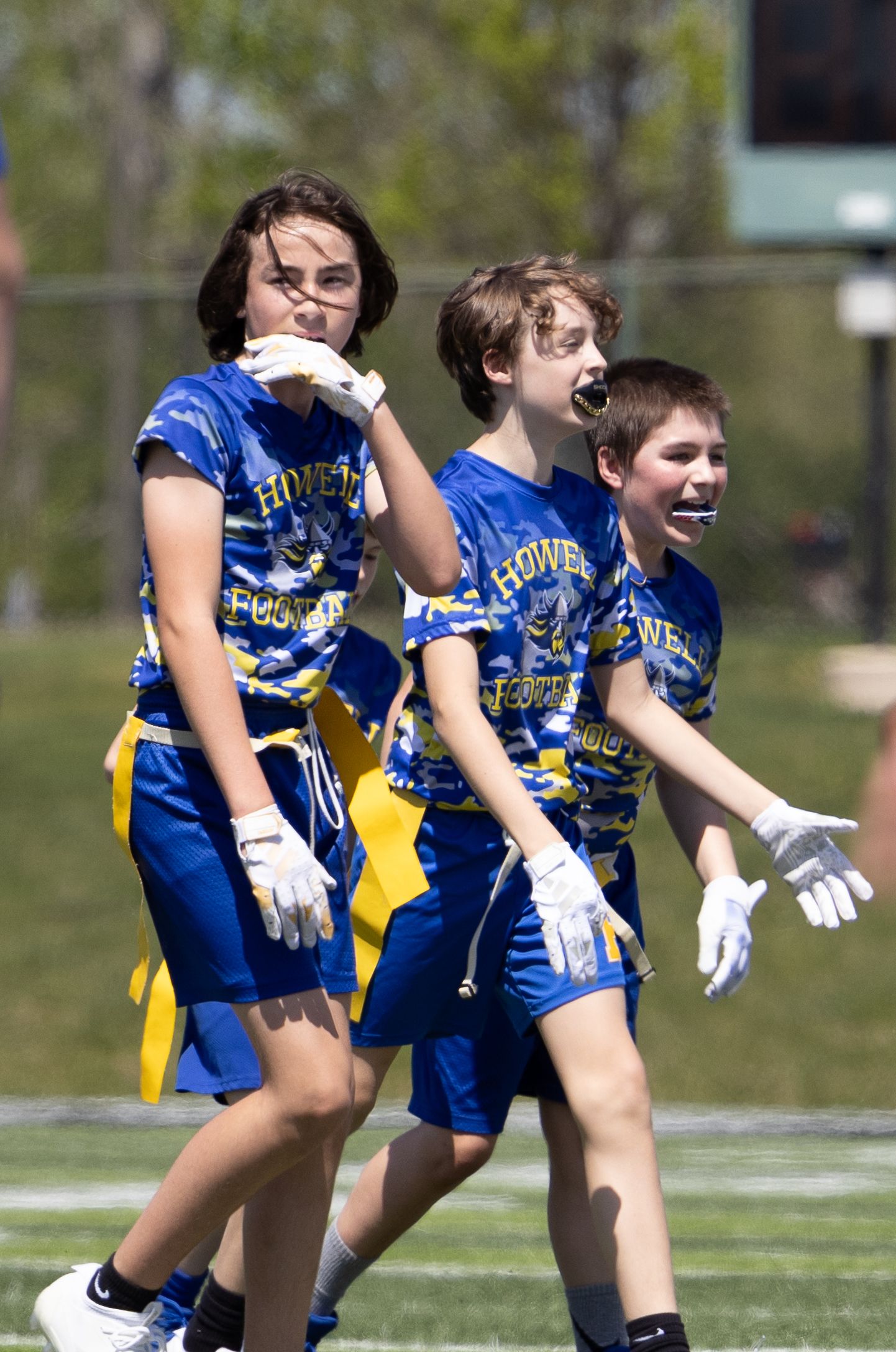 Youth ultimate frisbee players in blue jerseys reacting during a game.