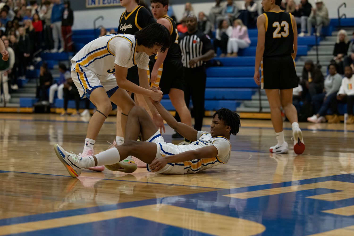 Basketball players scramble for possession of the ball on a blue court during an intense game.