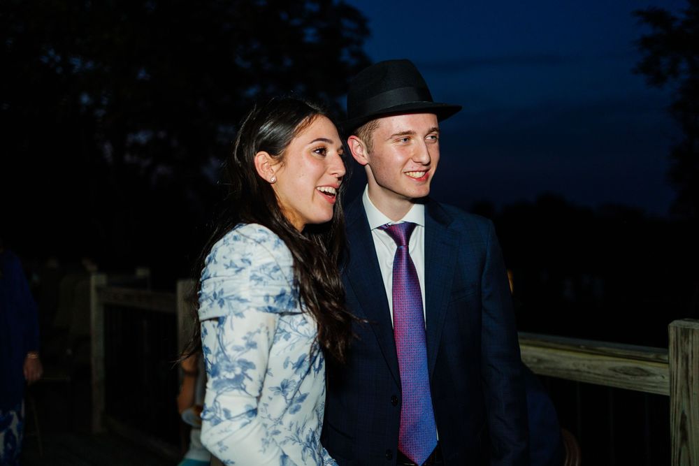 People standing outdoors at night engaged in conversation at what appears to be a formal evening event.