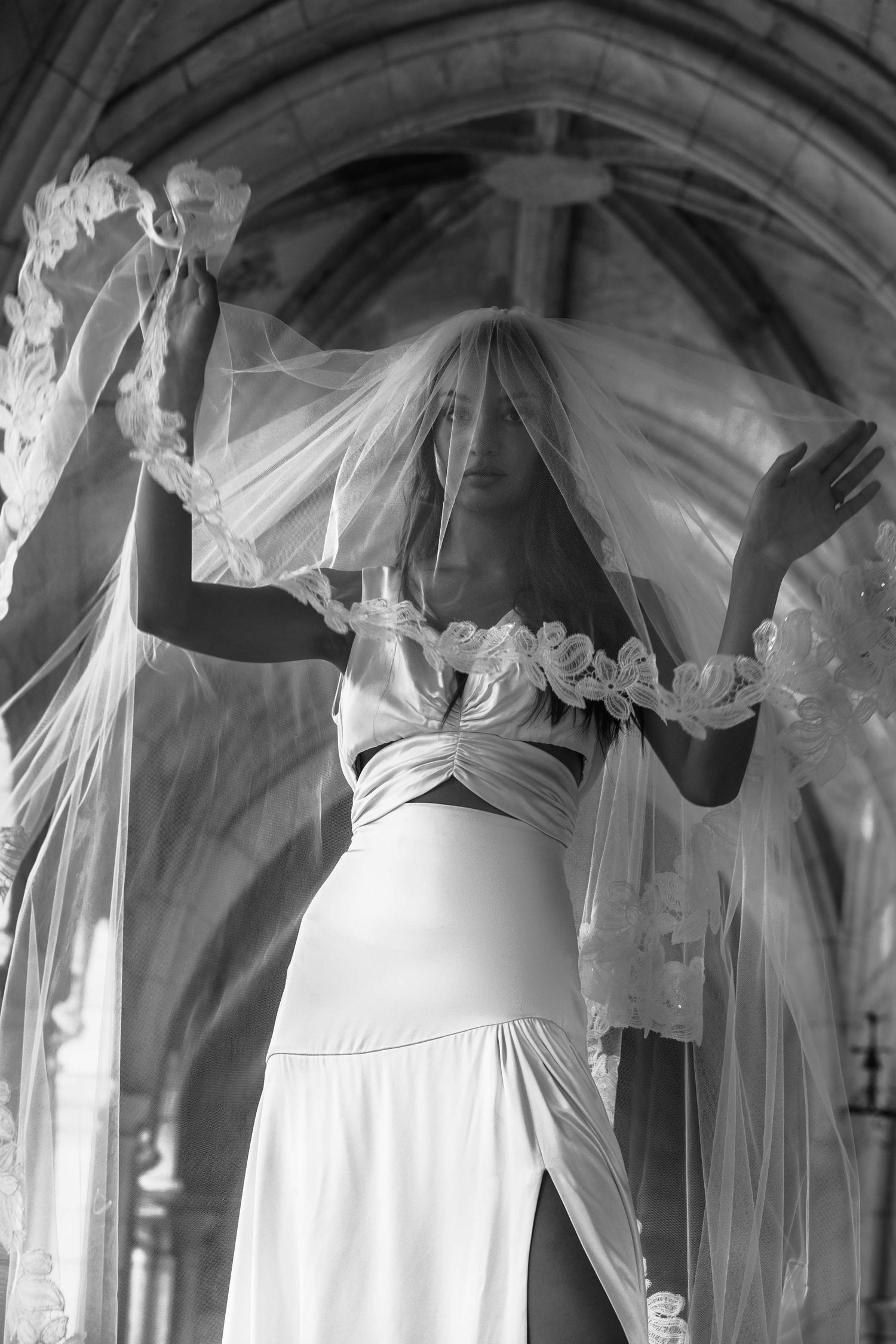 A collection of elegant white wedding dresses and veils displayed on hangers in a vintage-style interior.