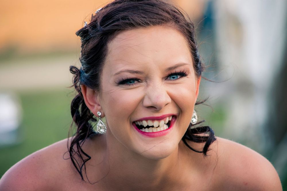A joyful woman in a wedding dress smiles radiantly, capturing the happiness and spirit of her special day.