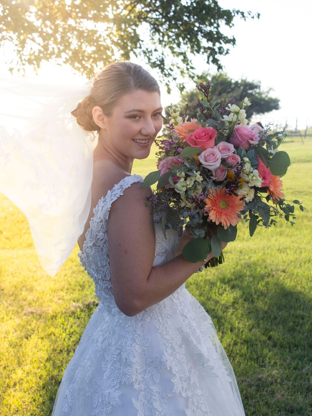 A joyful bride in a grassy setting, holding a beautiful bouquet of flowers, symbolizing love and celebration.