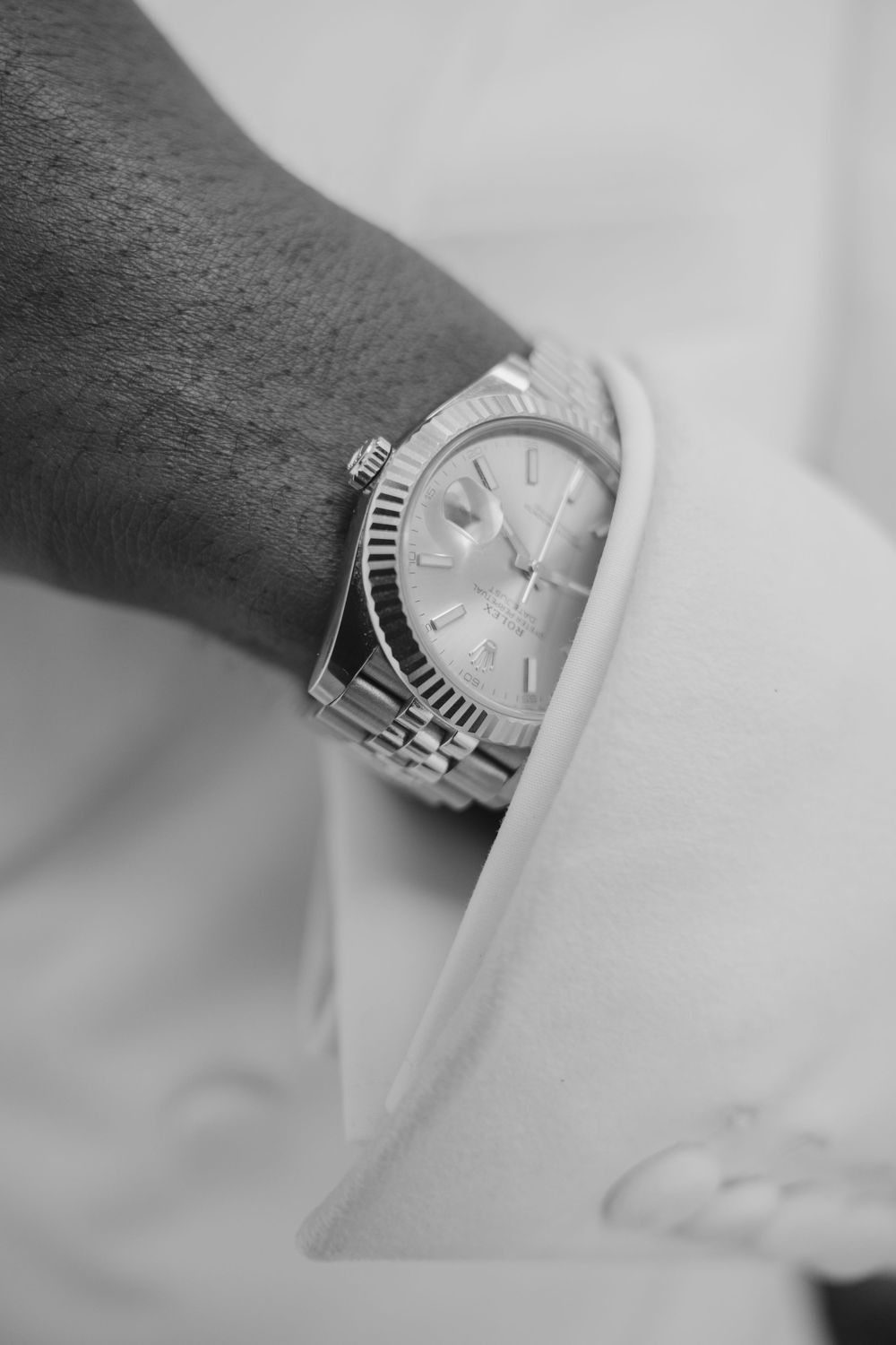 A silver watch worn on a wrist rotates through multiple angles in a series of black and white photographs.