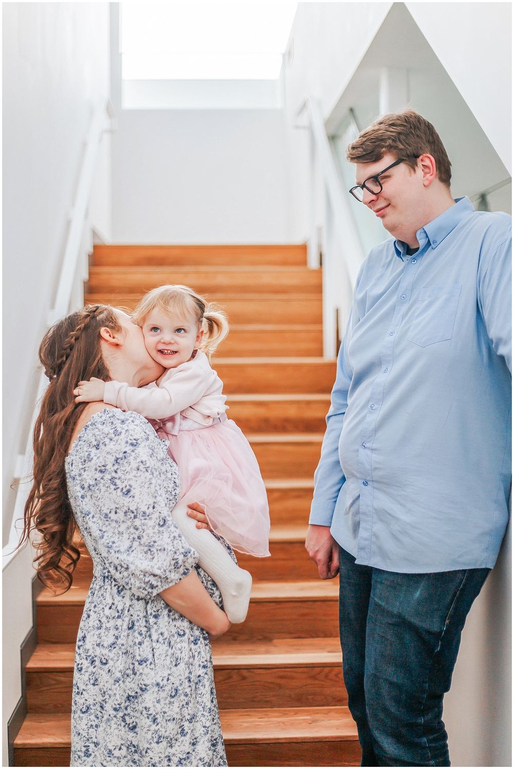 Family enjoying a sweet moment together on wooden stairs inside their bright and welcoming home.