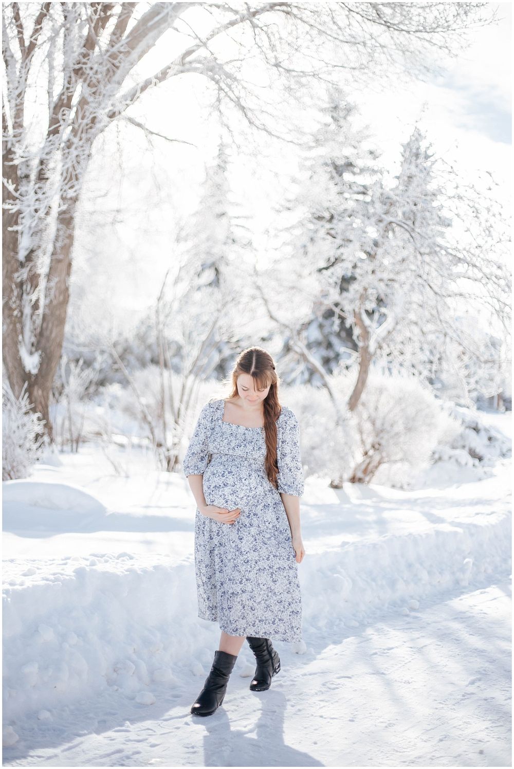 Winter outdoor portrait showcasing a floral dress and boots against a snowy backdrop with snow-covered birch trees.