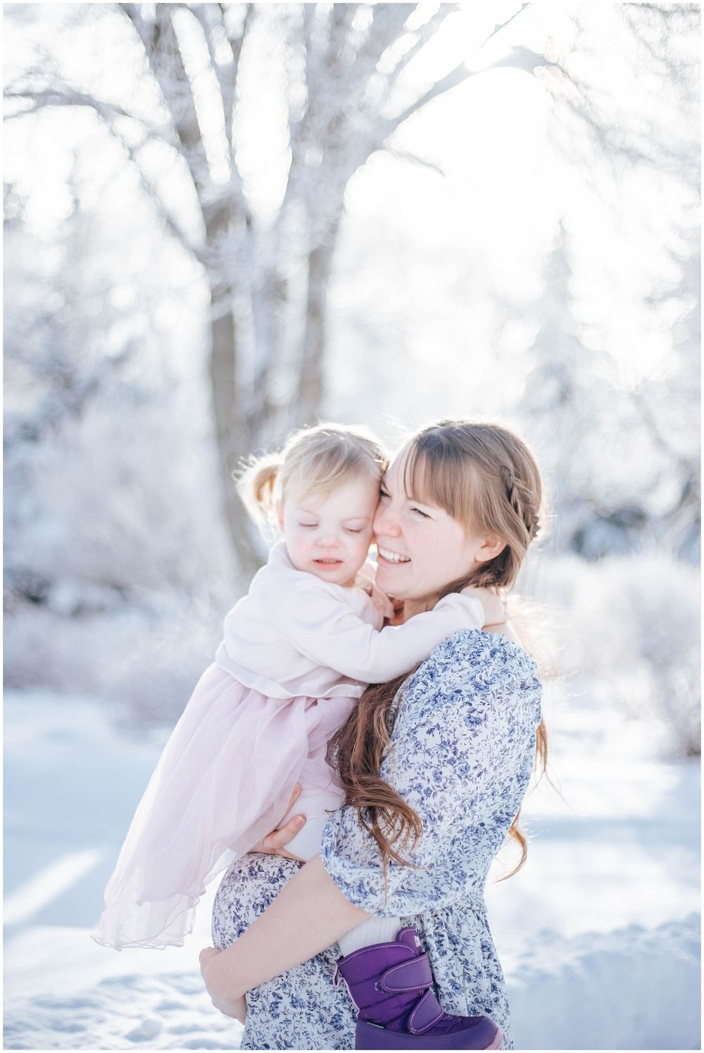 A touching winter portrait in the snow with soft lighting and dreamy white branches in the background.