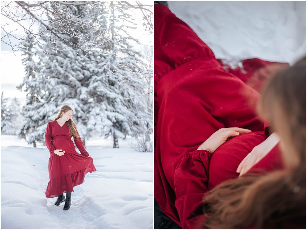 A flowing red dress creates dramatic contrast against a snowy winter forest landscape with snow-covered evergreen trees.