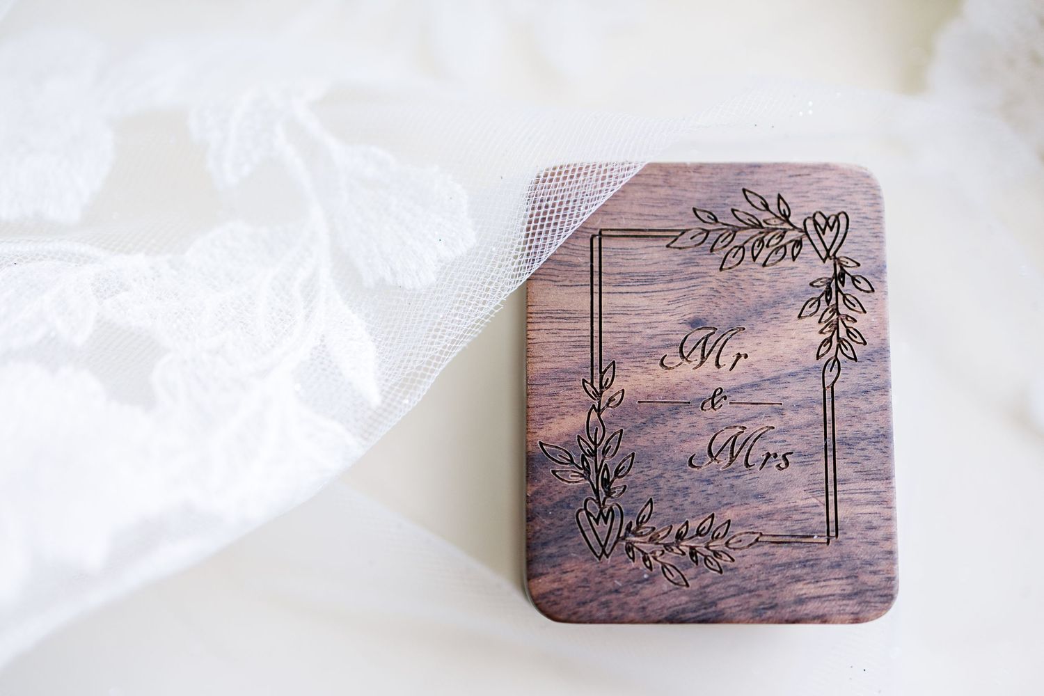 A wooden wedding ring box with 'Mr & Mrs' text and floral design engraved on top.