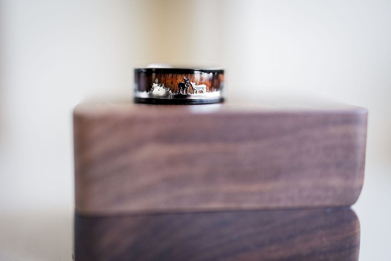 Close-up of a black wedding band on a wooden surface.