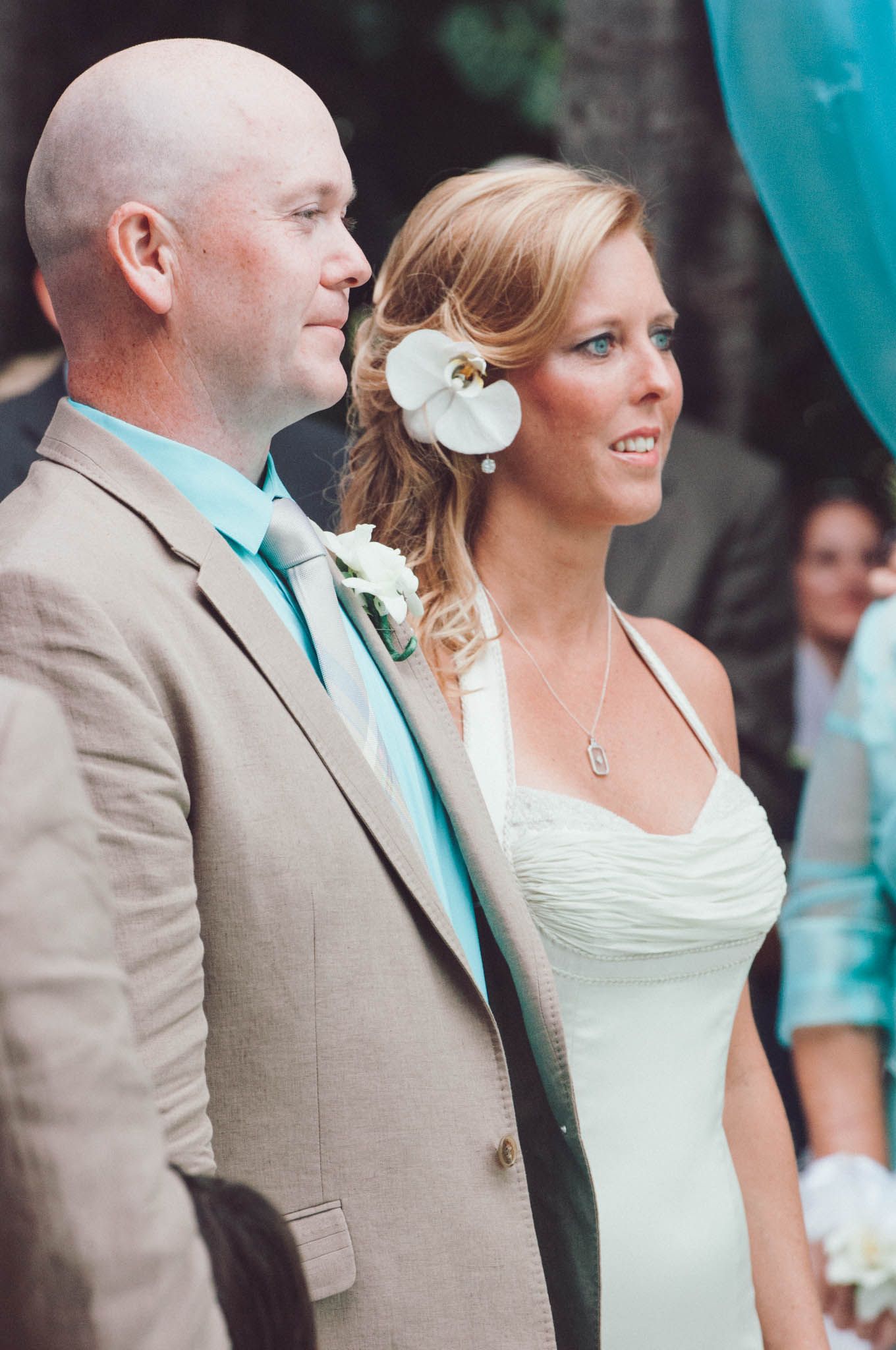A couple in wedding attire poses together during their outdoor ceremony.
