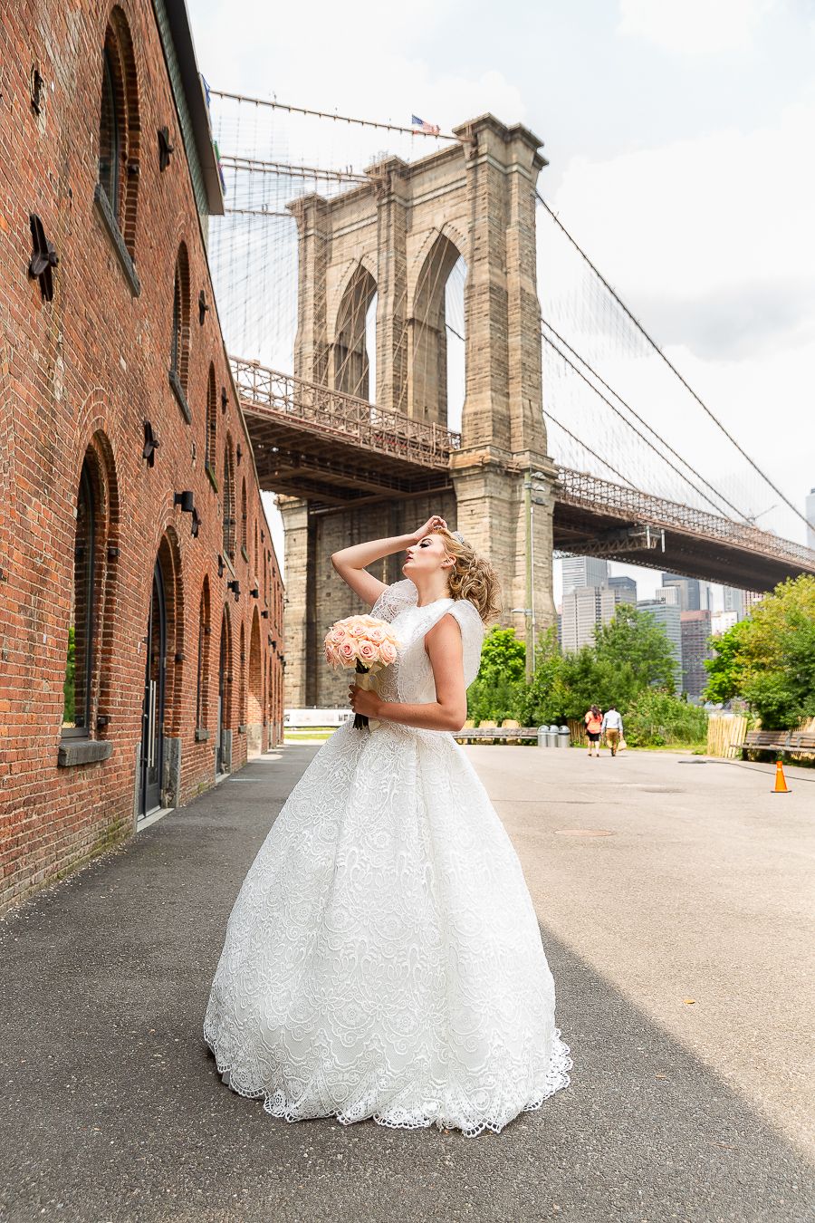 Classic bridal portrait with Brooklyn Bridge and brick architecture creating dramatic urban backdrop.