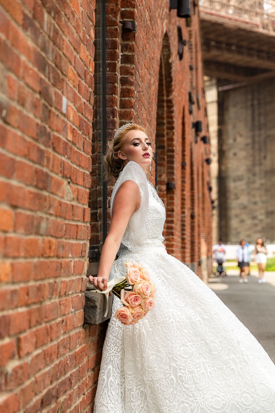 An artistic bridal portrait showing intricate lace details against historic brick architecture.