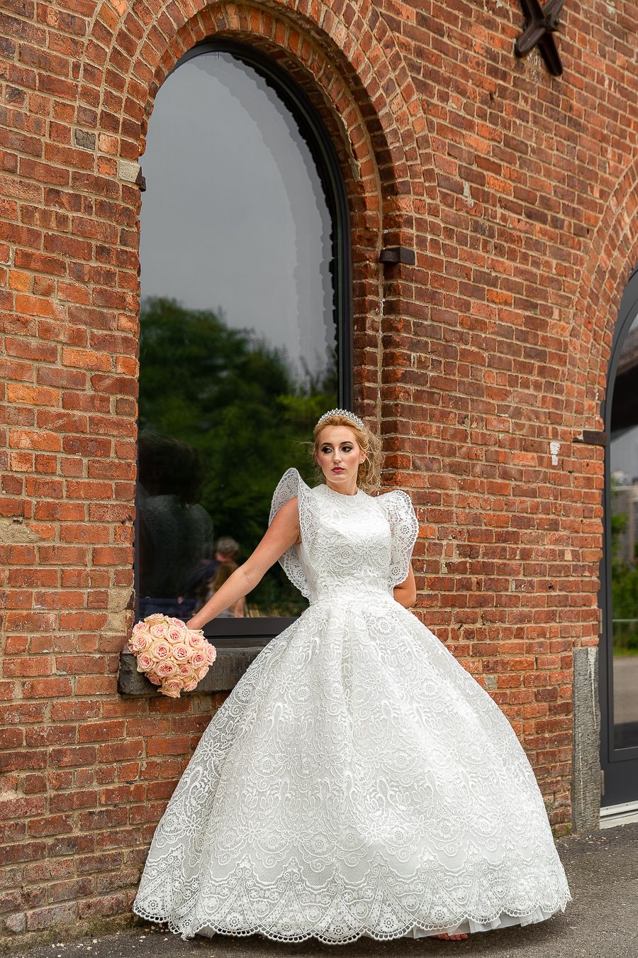 A timeless bridal portrait featuring a ball gown wedding dress framed by an arched brick doorway.